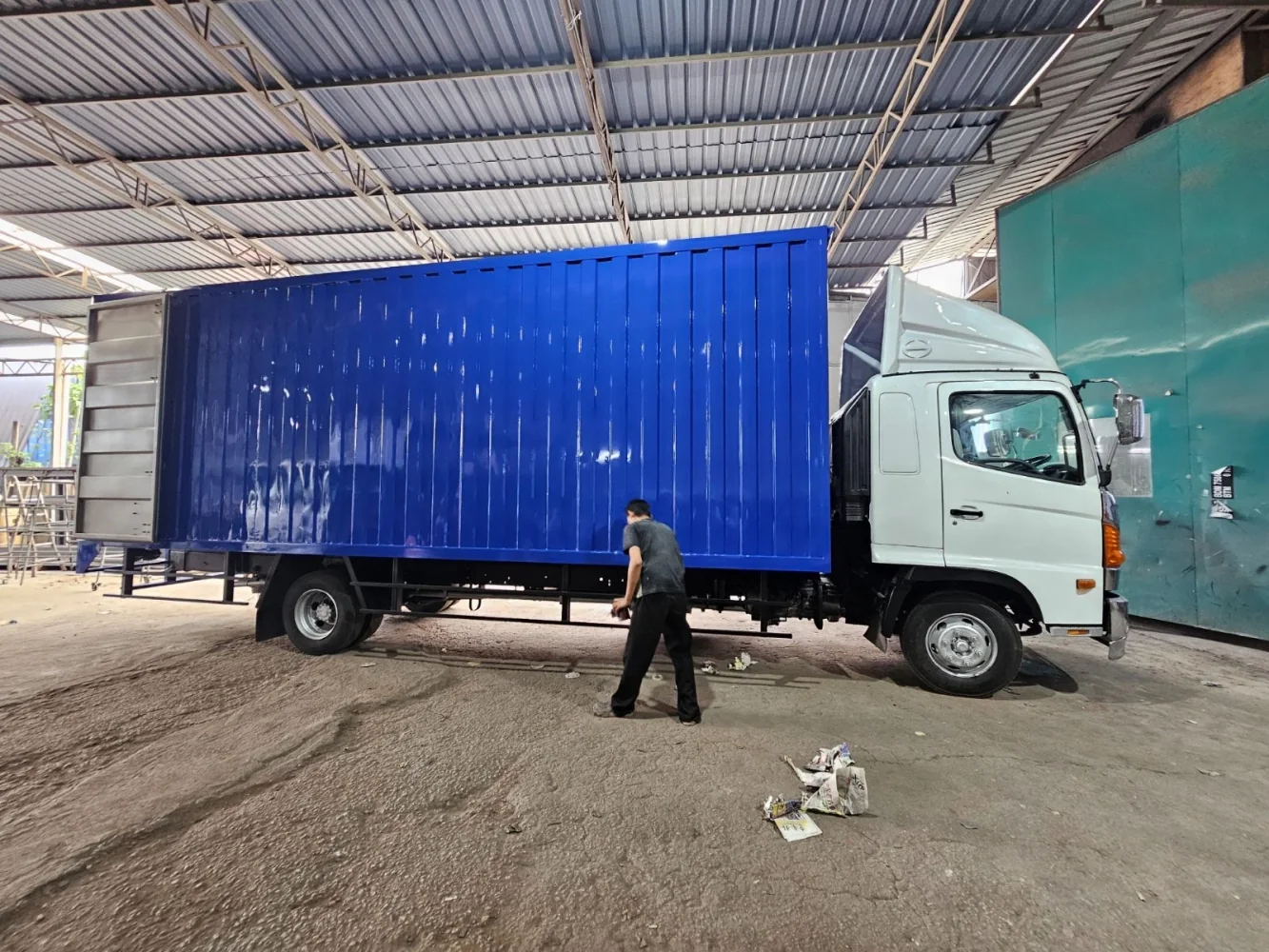 Blue enclosed cargo body on a white truck in the workshop