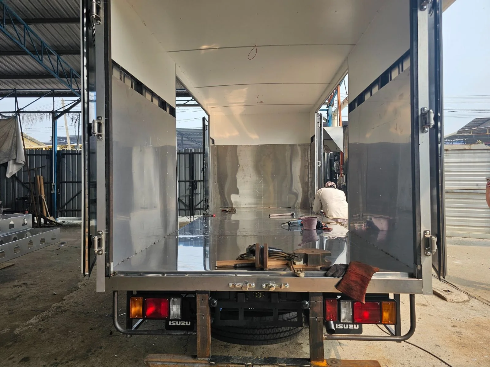 View through open rear doors into a truck cargo body during interior finishing